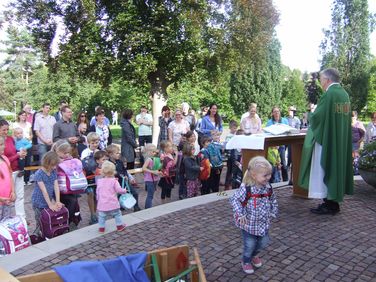 Kinder warten auf die Segnung ihrer Schulranzen und Kindergartenrucksäcke